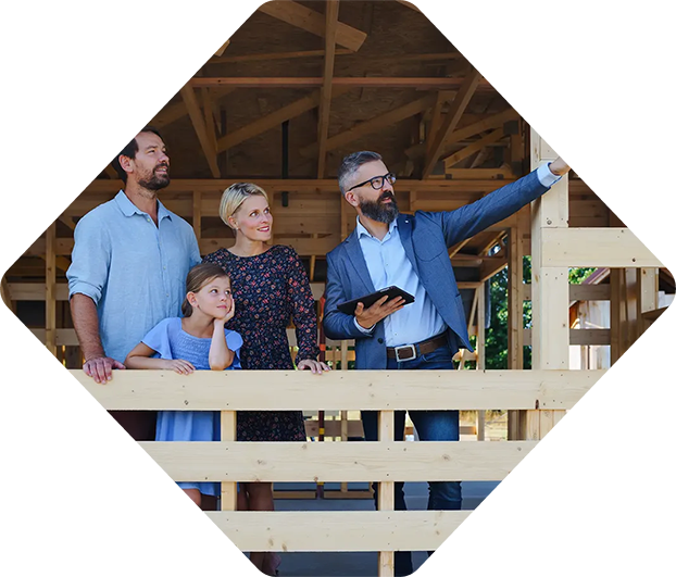 Famille et agent immobilier sur un chantier de construction ; l'agent immobilier montre la structure en bois.