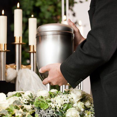 Religion, death and dolor - mortician on funeral with urn