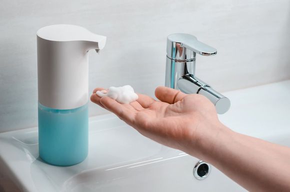 a person taking the soap from the handwash dispenser