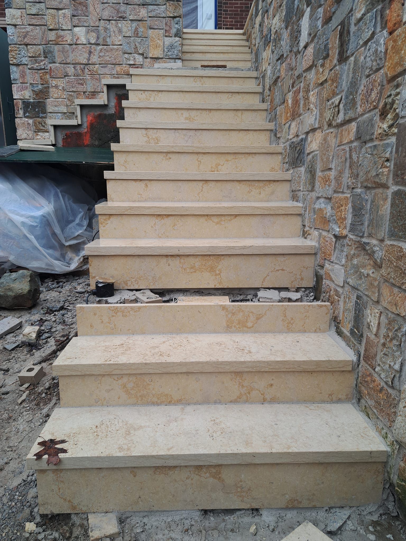 Stone staircase ascending the side of a building with stone exterior.
