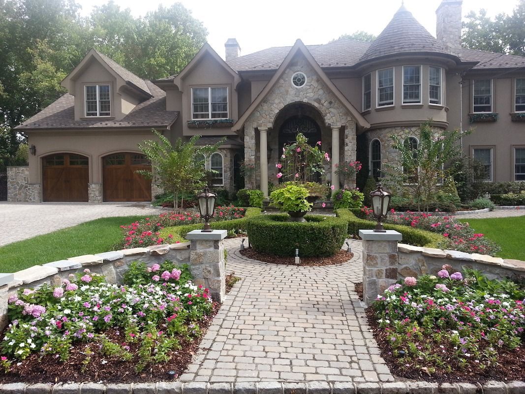Elegant house with manicured landscaping, stone walkway, and flower beds.