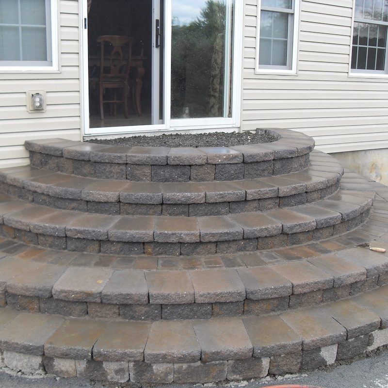 Stone steps leading up to a sliding glass door. The steps are curved and gray-brown.