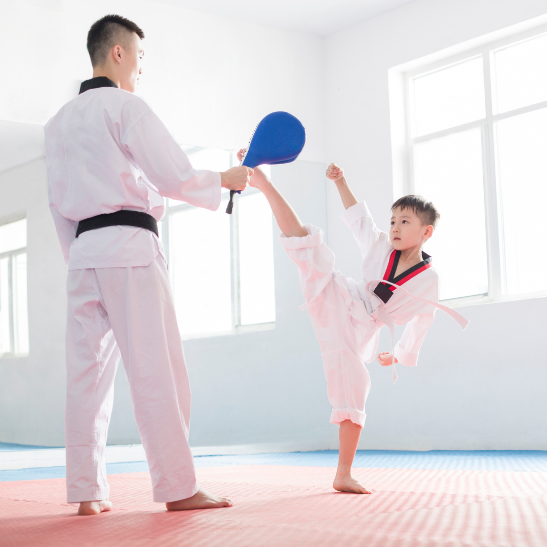 A group of children are practicing karate with a teacher in a gym.