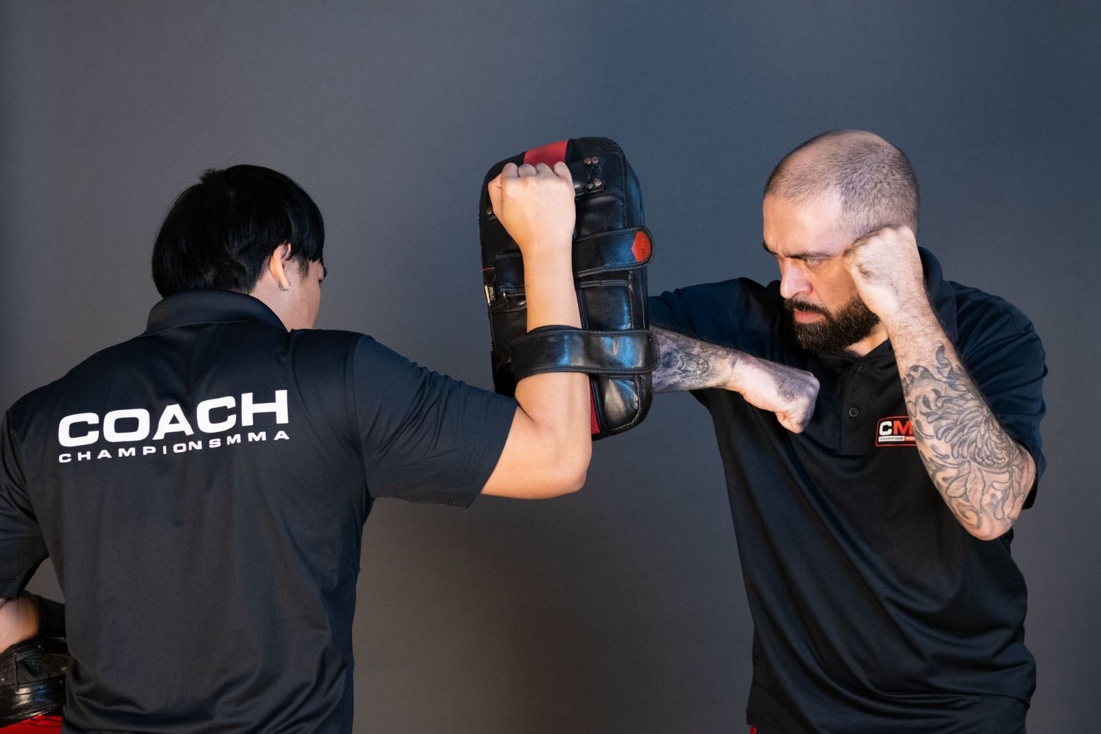 Two men in karate uniforms are posing for a picture in a gym.