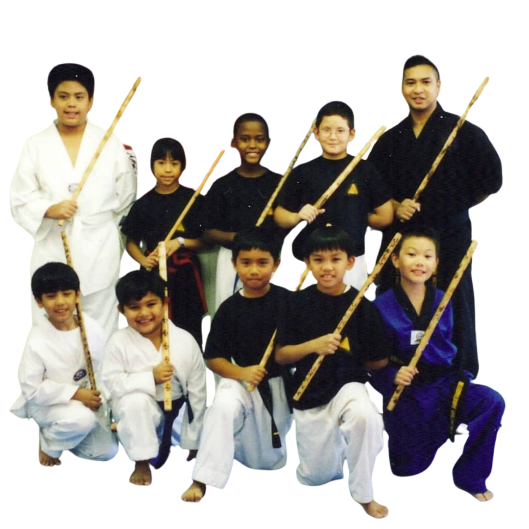 A boy and two girls are wearing karate uniforms and pointing at the camera