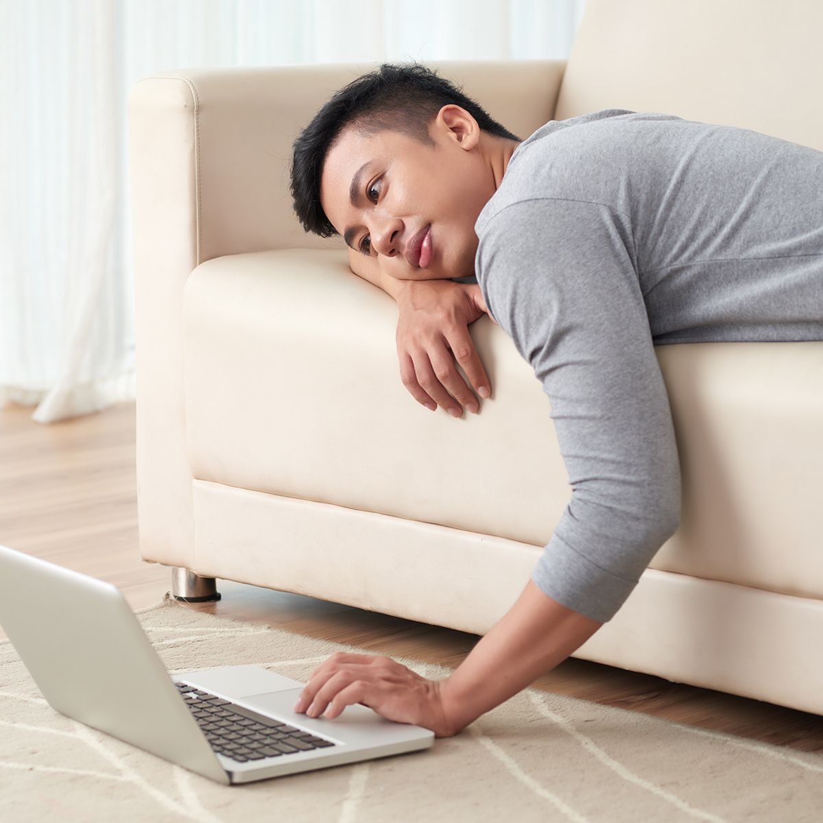 A man laying on a couch using a laptop