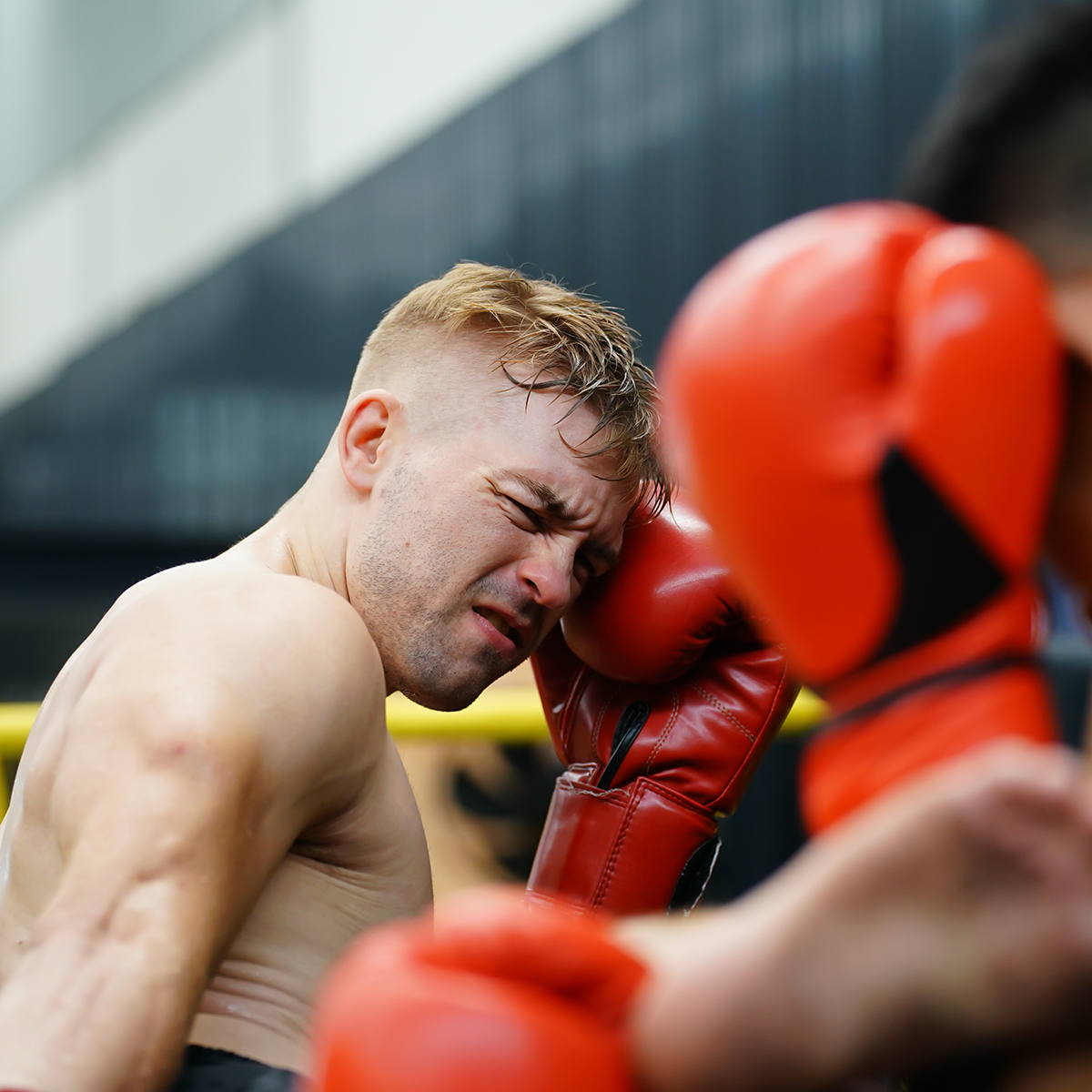 a man dodging hits in self defense while wearing boxing gloves