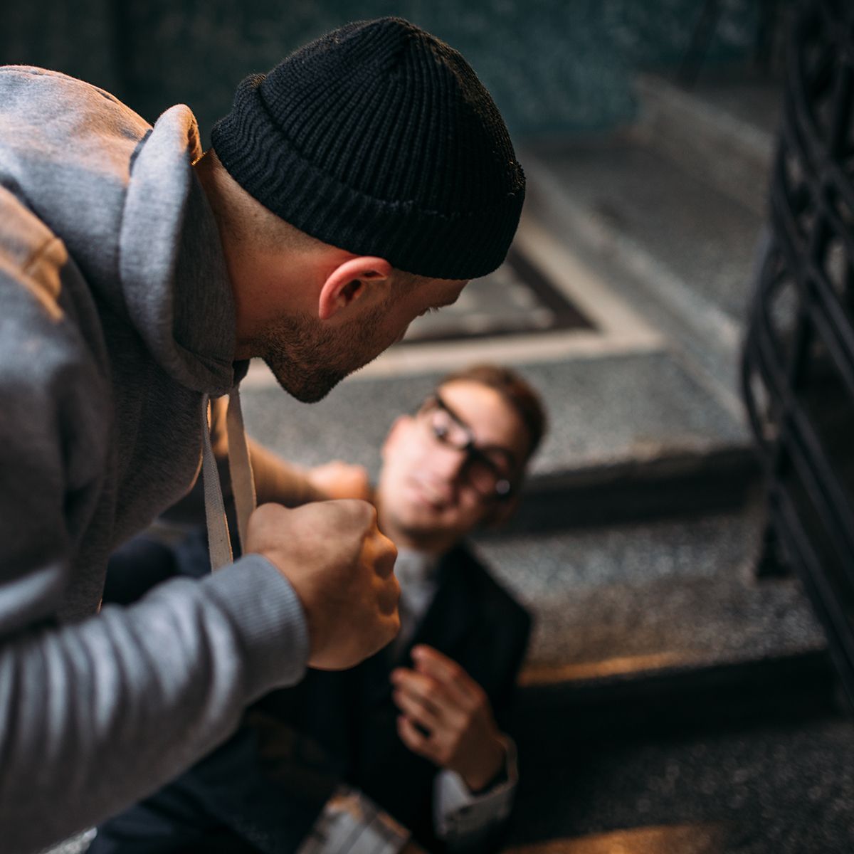 A man in a black hat is standing next to a man in a suit on a set of stairs.