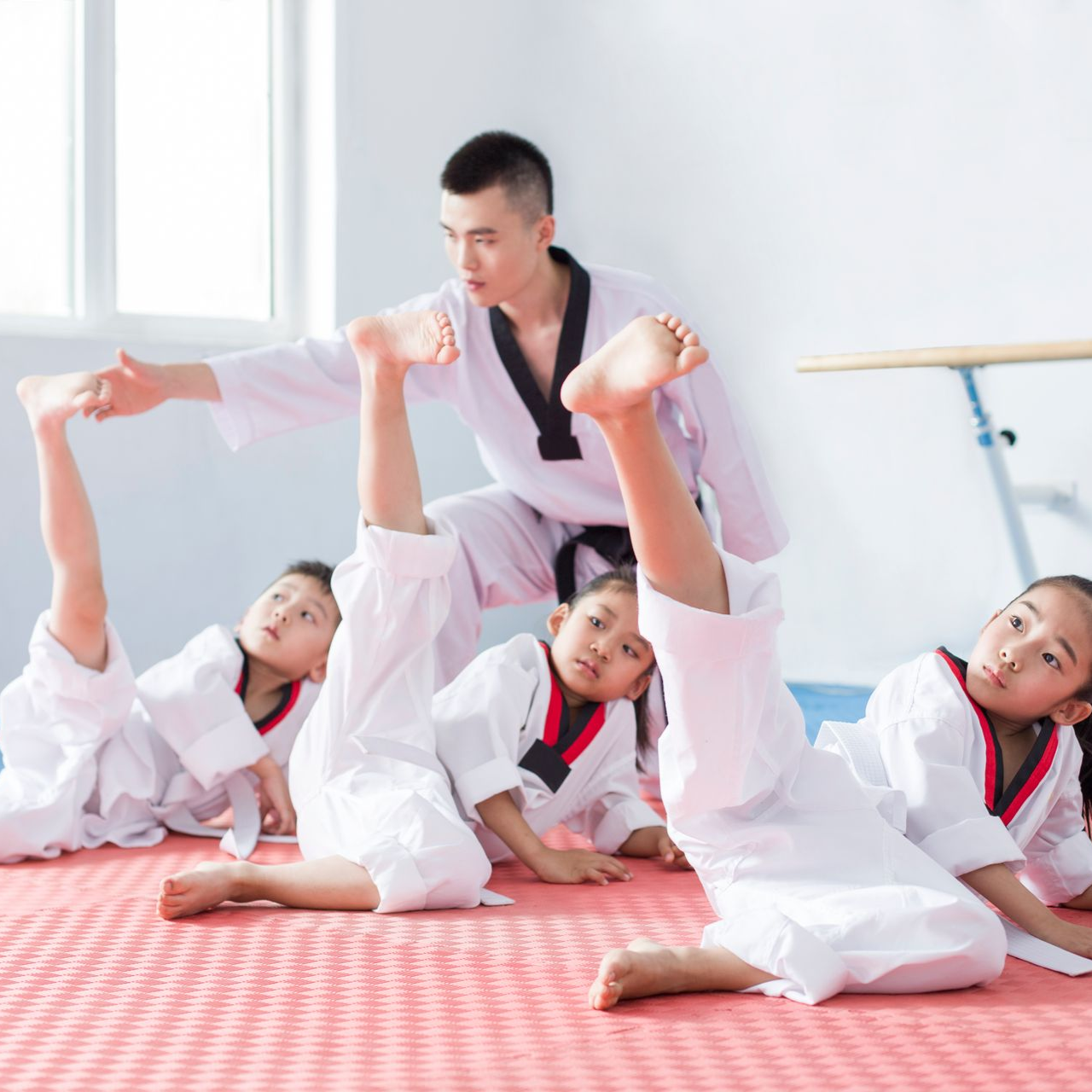 A young girl in a karate uniform is sitting on the floor.