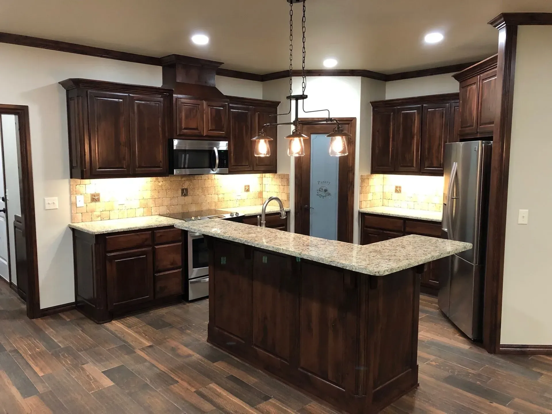 A kitchen with wooden cabinets , granite counter tops , stainless steel appliances and a large island.