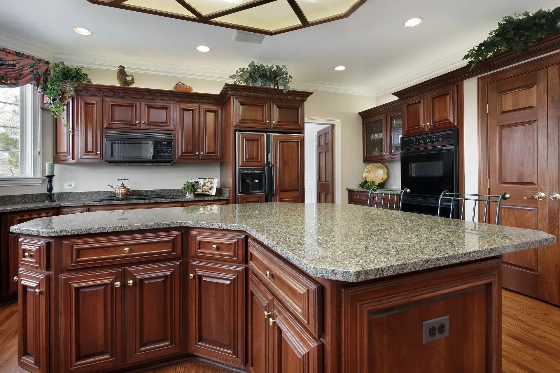 A kitchen with wooden cabinets , granite counter tops , stainless steel appliances and a large island.