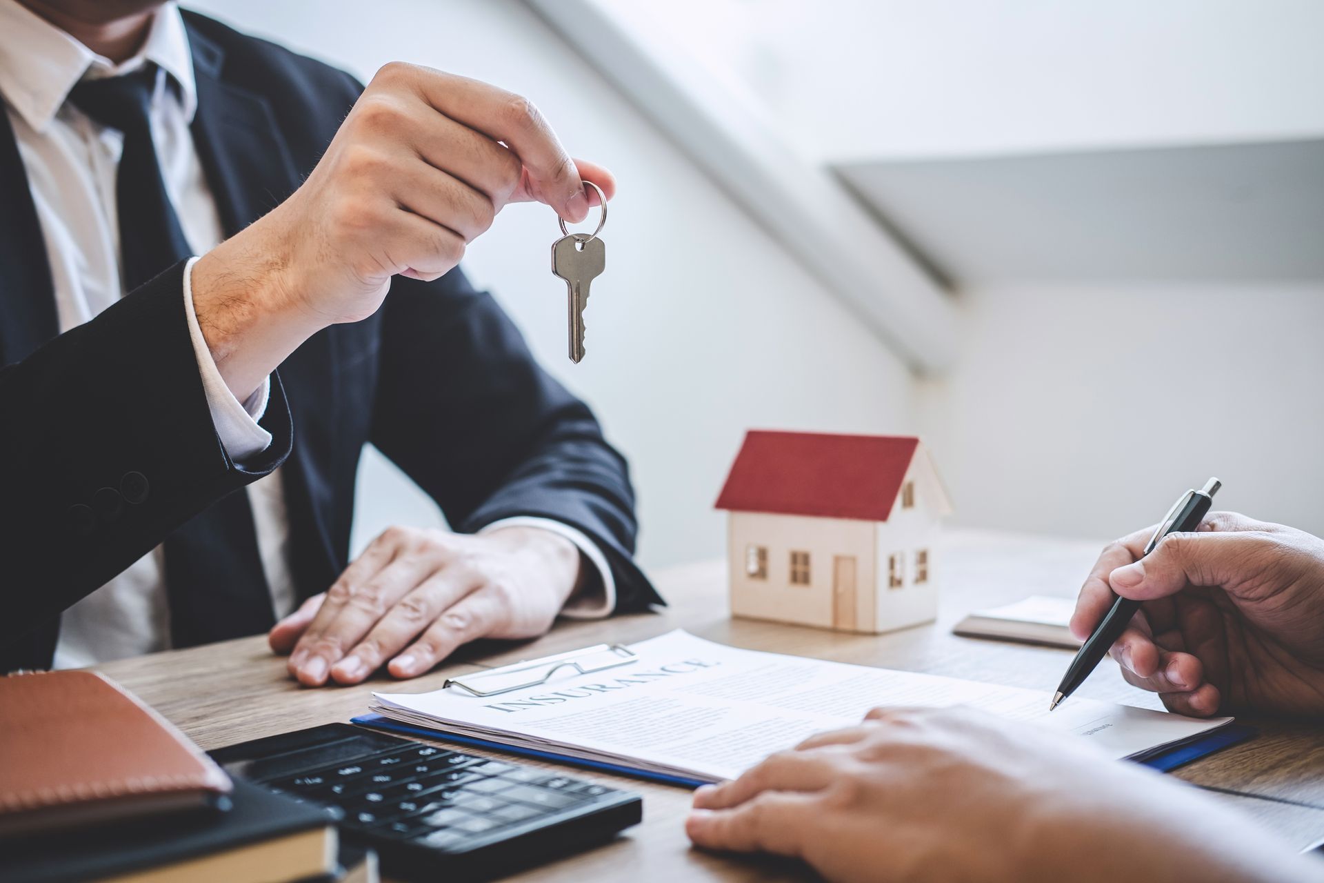 Business people exchanging keys over house model during a real estate meeting