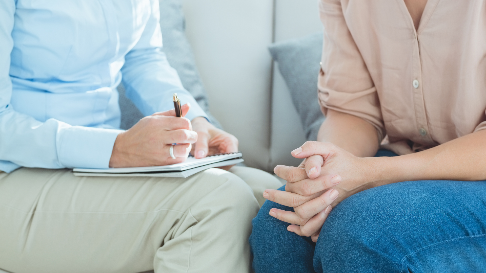 A man is sitting next to a woman on a couch and talking to her.