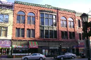 A white car is parked in front of a brick building