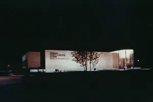 A building is lit up at night with a tree in front of it.