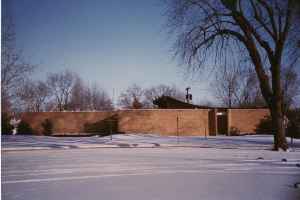A brick building is surrounded by snow and trees
