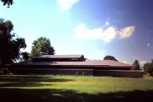 A large building is sitting in the middle of a lush green field.