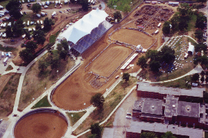 An aerial view of a dirt field with a large white tent in the middle