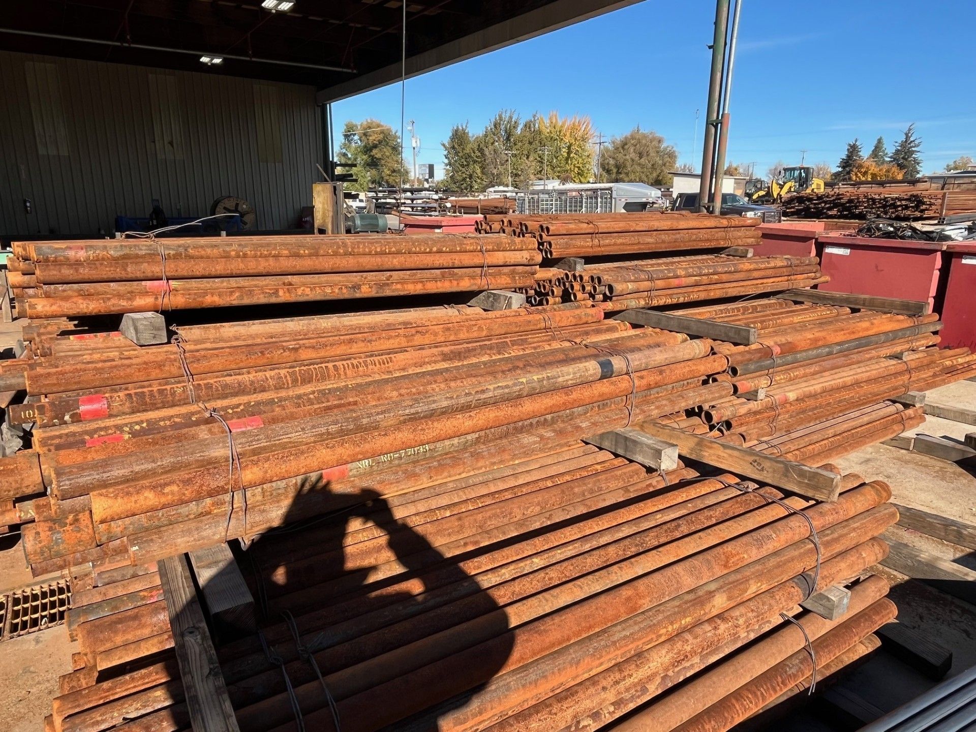A bunch of pipes are stacked in front of a building that says rocky mountain steel