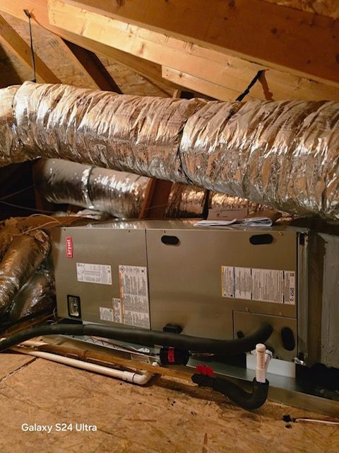 HVAC unit in an attic with ductwork, wooden beams, and condensation drain pipes.