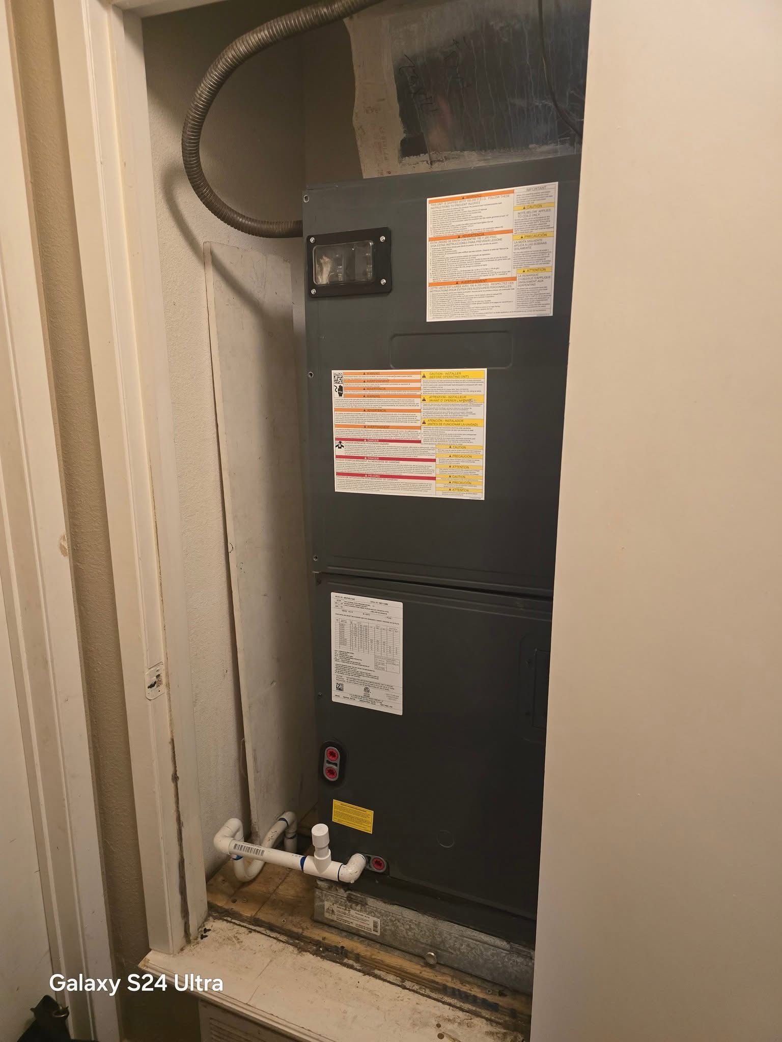 Furnace in a utility closet with pipes and ductwork visible.