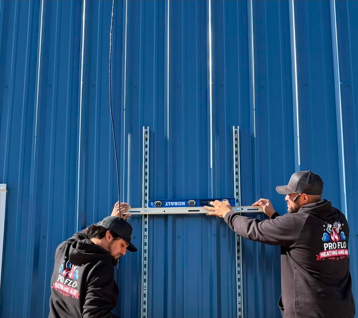 Two gray HVAC units with ductwork in a room with a window and a door.
