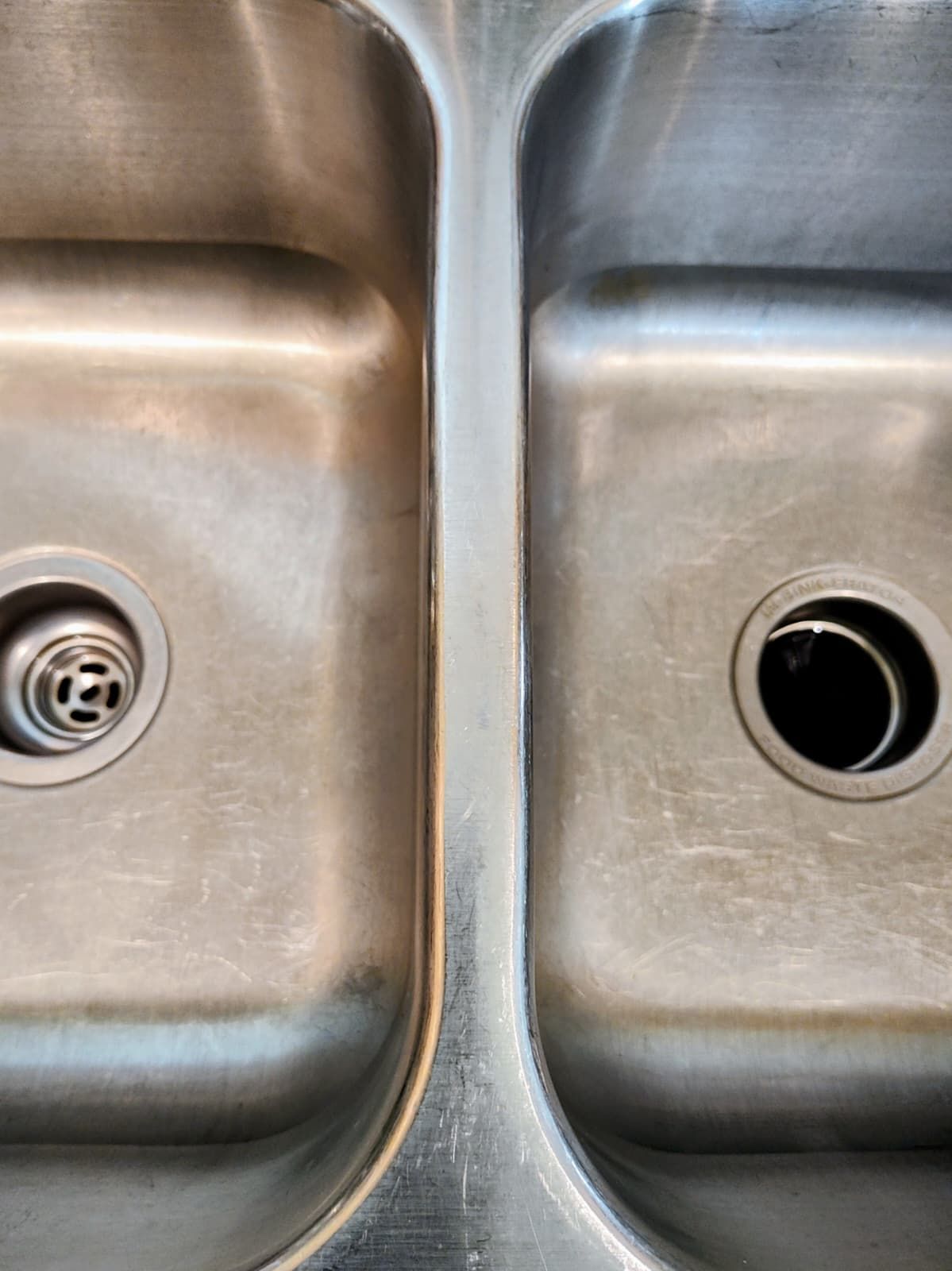 Stainless steel double kitchen sink with drains visible, close-up view
