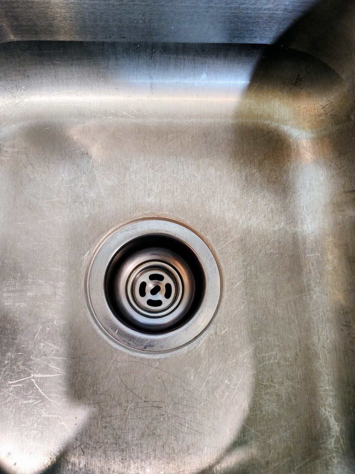 Stainless steel sink basin with a drain centered in the frame.