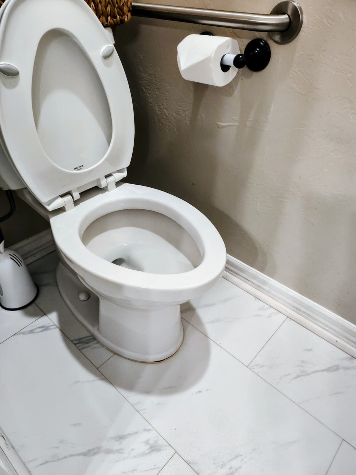 Accessible bathroom with a white toilet, grab bar, toilet paper holder, and tiled floor