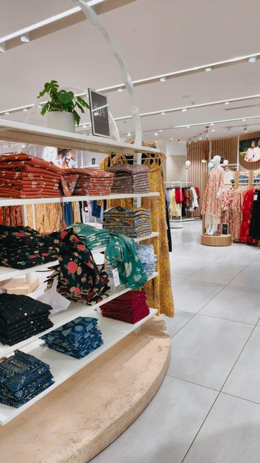 Clothing store interior with shelves of folded colorful sweaters and racks of hanging garments