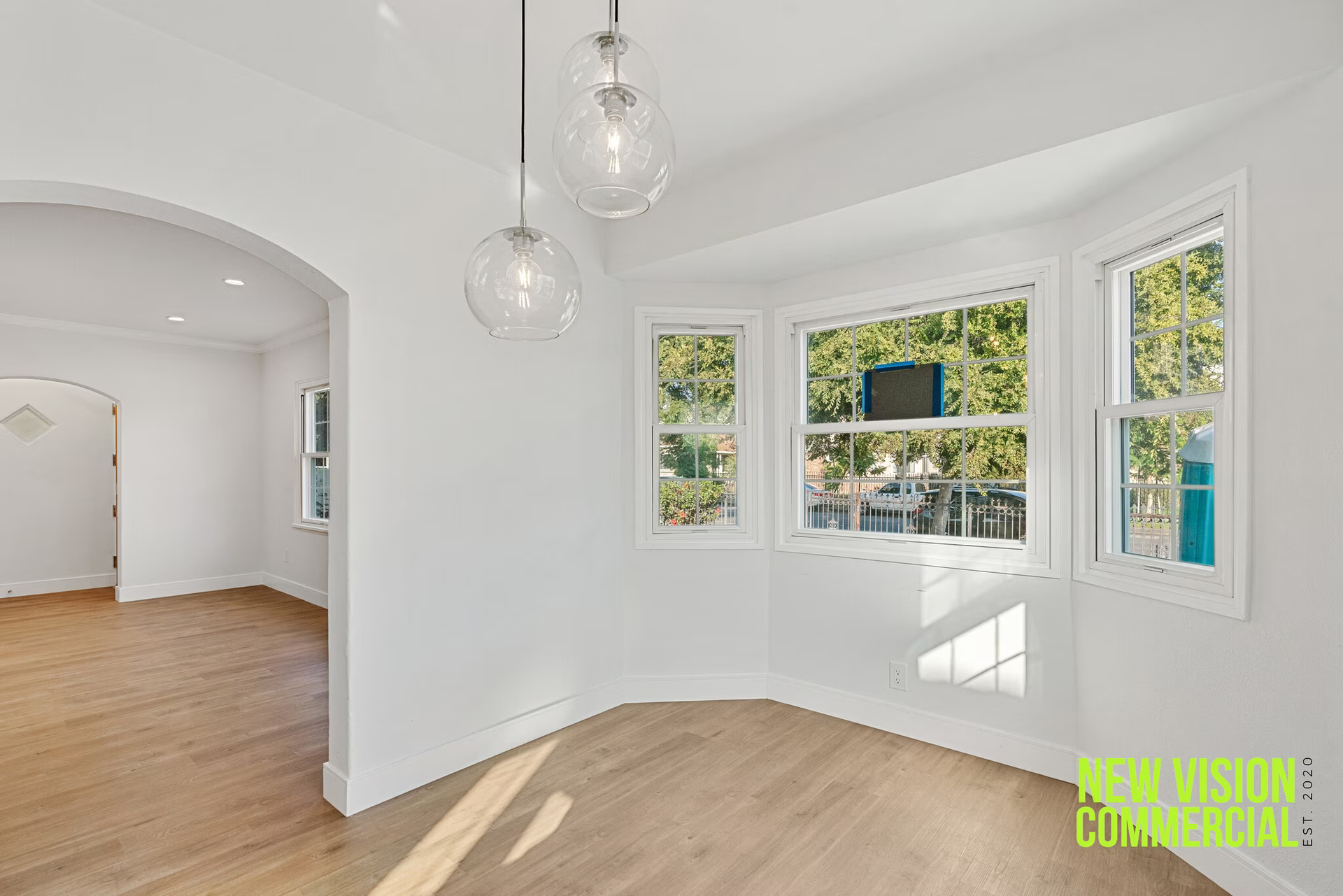 An empty room with a lot of windows and a wooden floor.