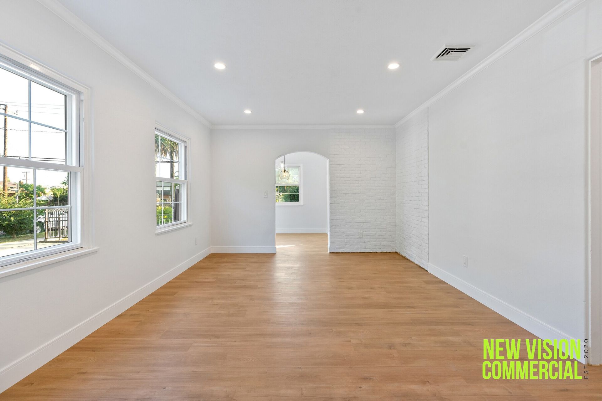 An empty living room with hardwood floors and white walls.
