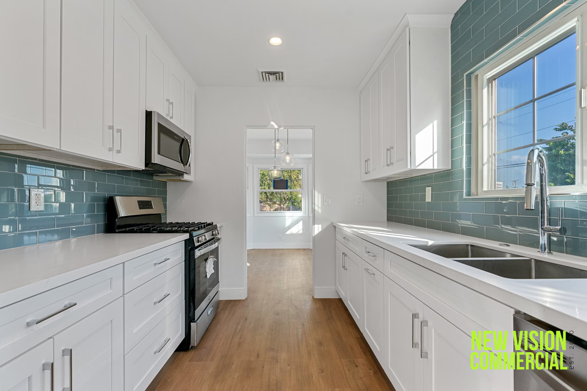 A kitchen with white cabinets , a stove , a sink , and a window.