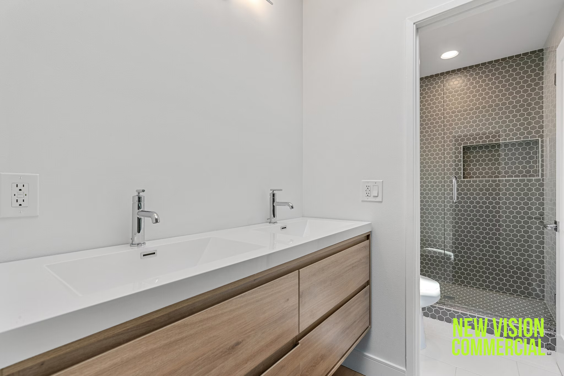 A bathroom with two sinks and a walk in shower.