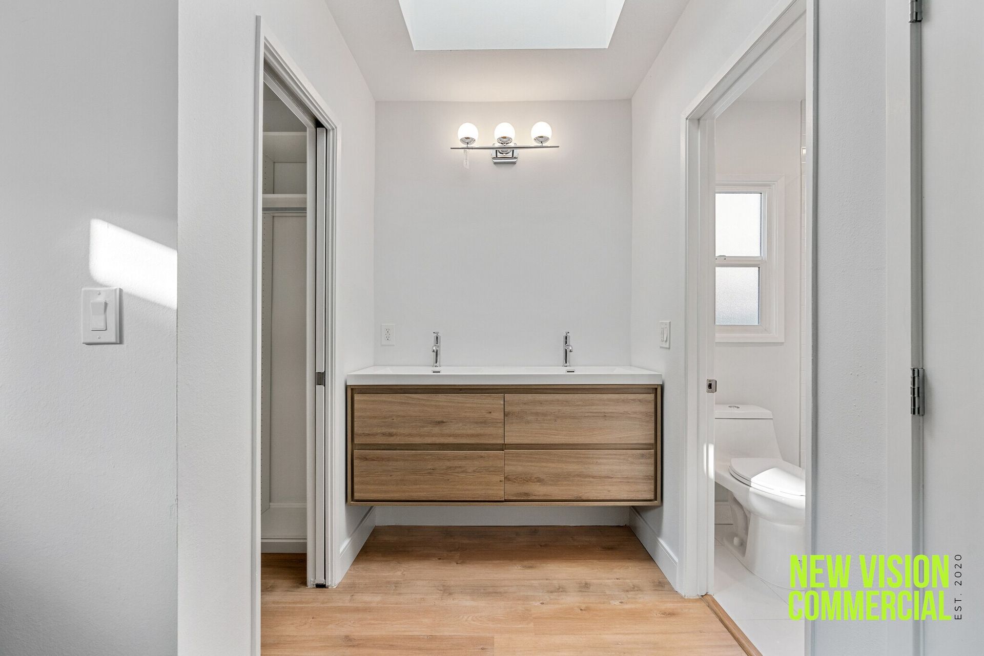A bathroom with two sinks , a toilet and a skylight.