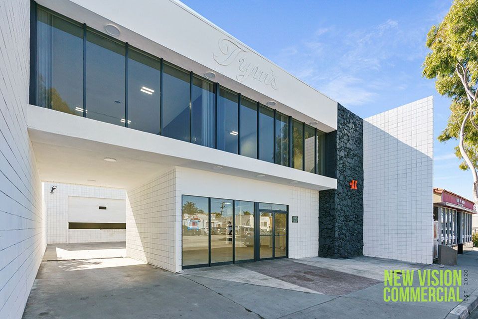 A large white building with a lot of windows and a sign that says new vision commercial