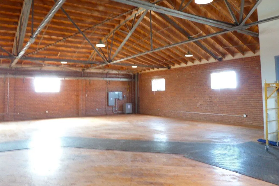 An empty warehouse with a wooden ceiling and brick walls