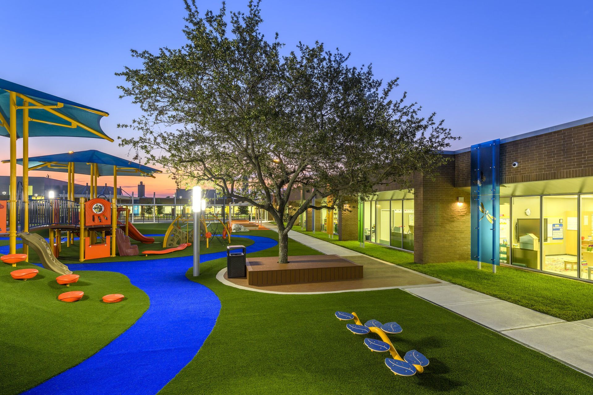 Playground with blue and green turf, play structures, and a building.