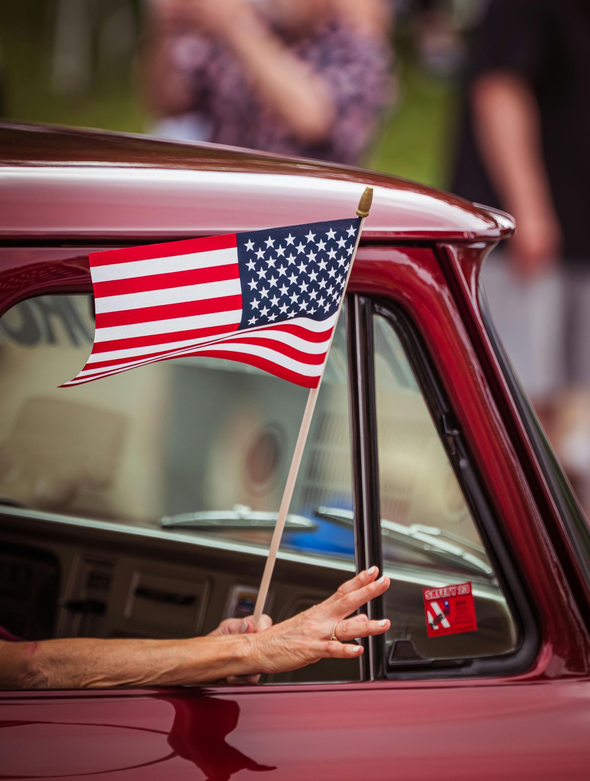 American flag held out a car window of a red car | TRC Automotive in Belmont, NC