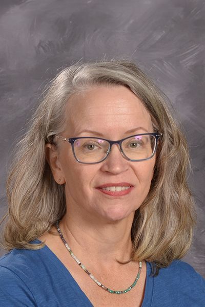 Head shot of smiling Kathy Kolell in a blue shirt