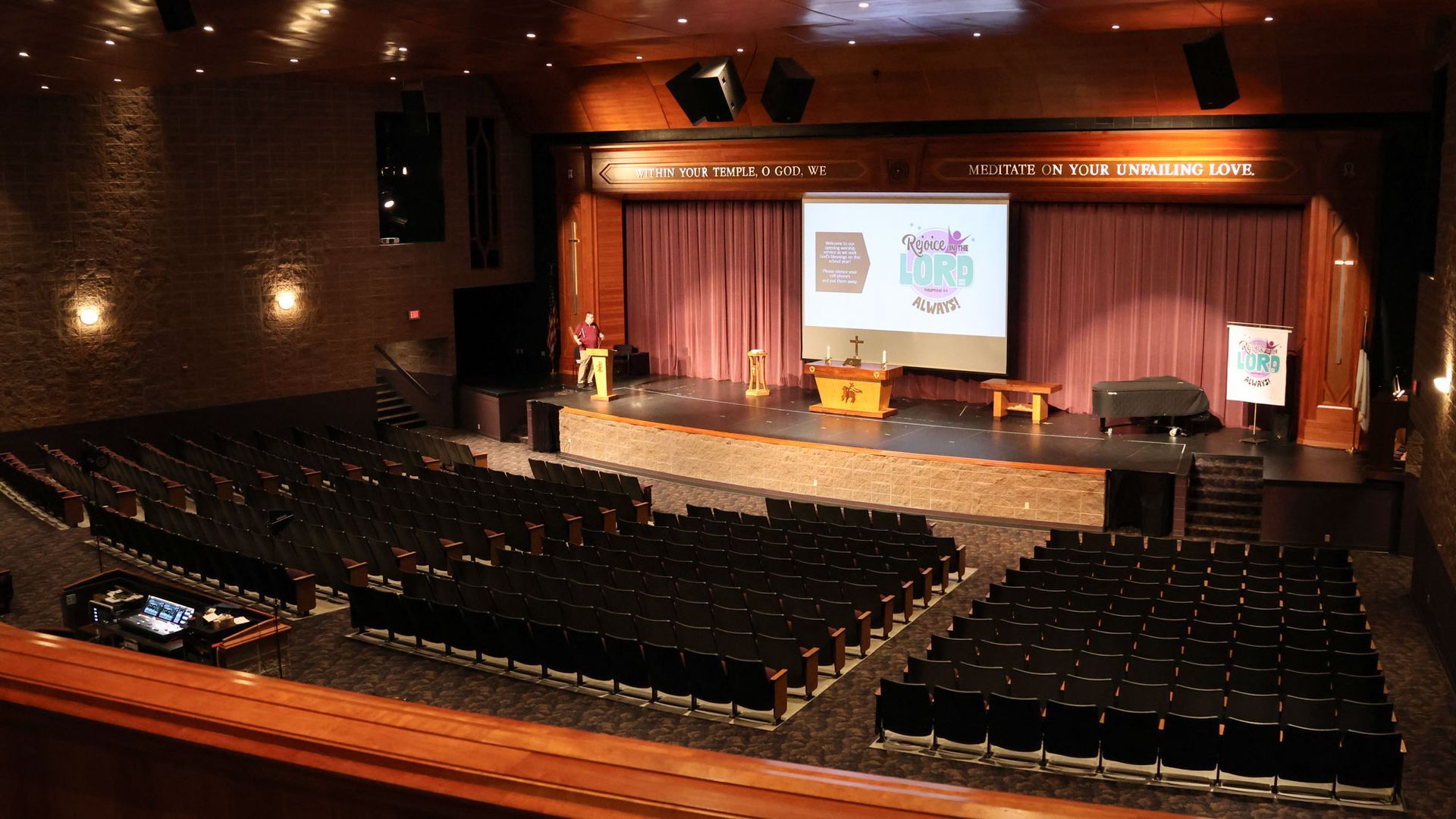 Interior of the auditorium, facing the stage, photo from the balcony, stage has screen down with theme logo