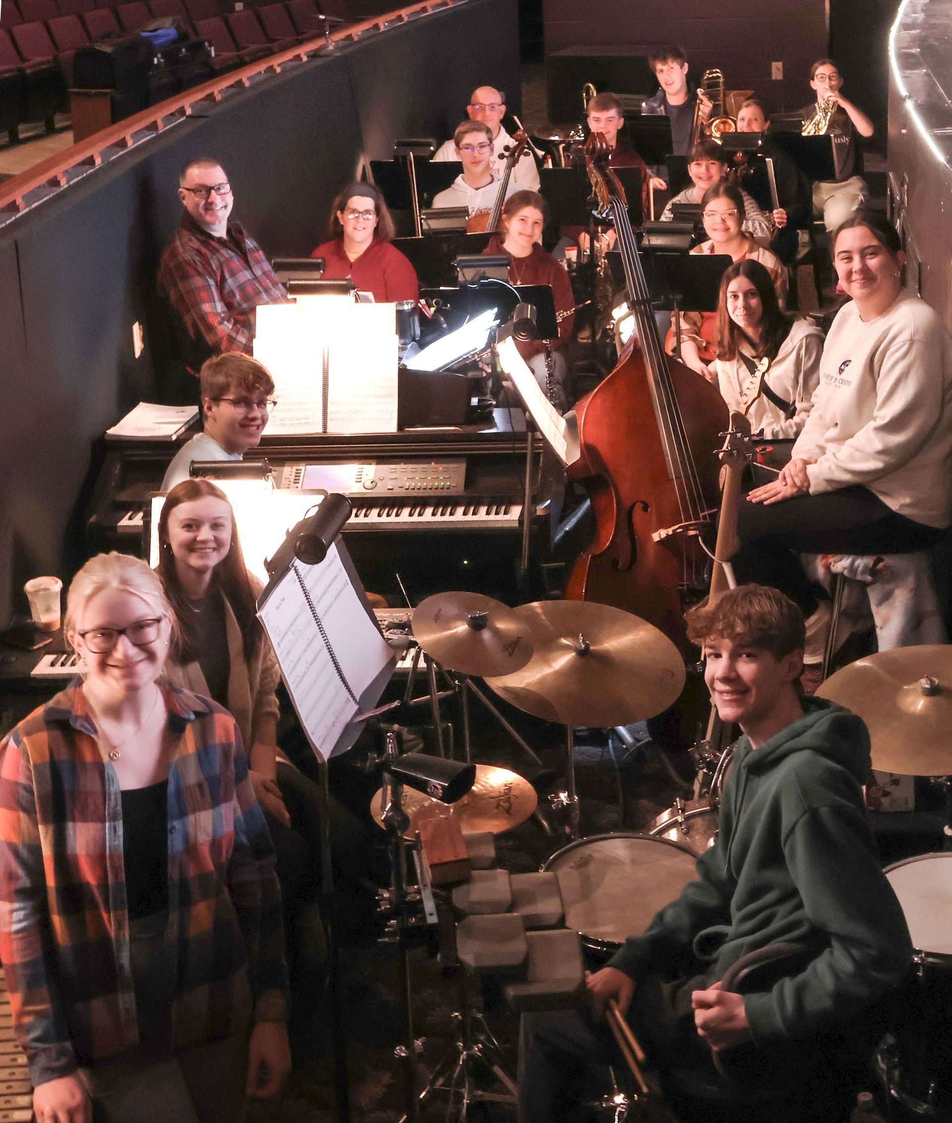Smiling orchestra members in the pit, looking at the camera.