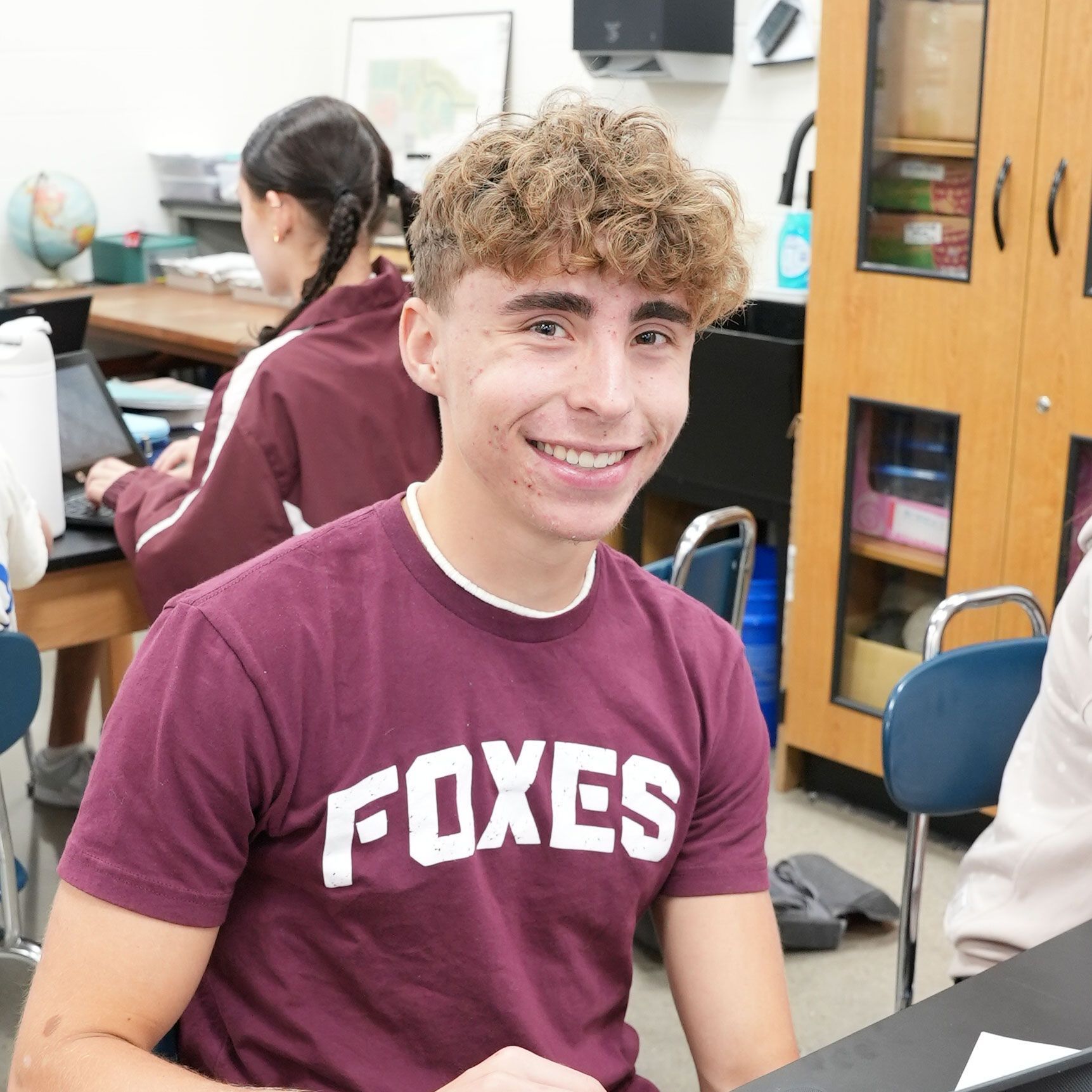 Smiling male student sitting at a science table and smiling
