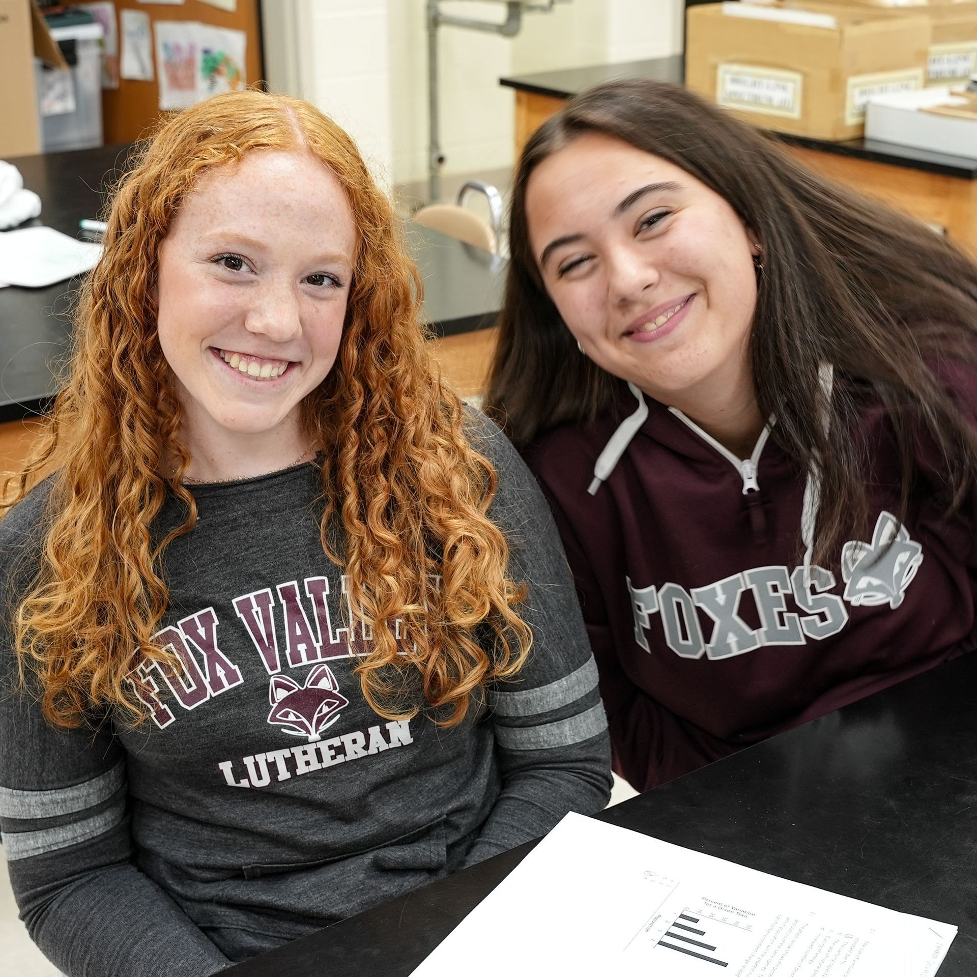 Two happy girls, smiling at the camera, while at a science table