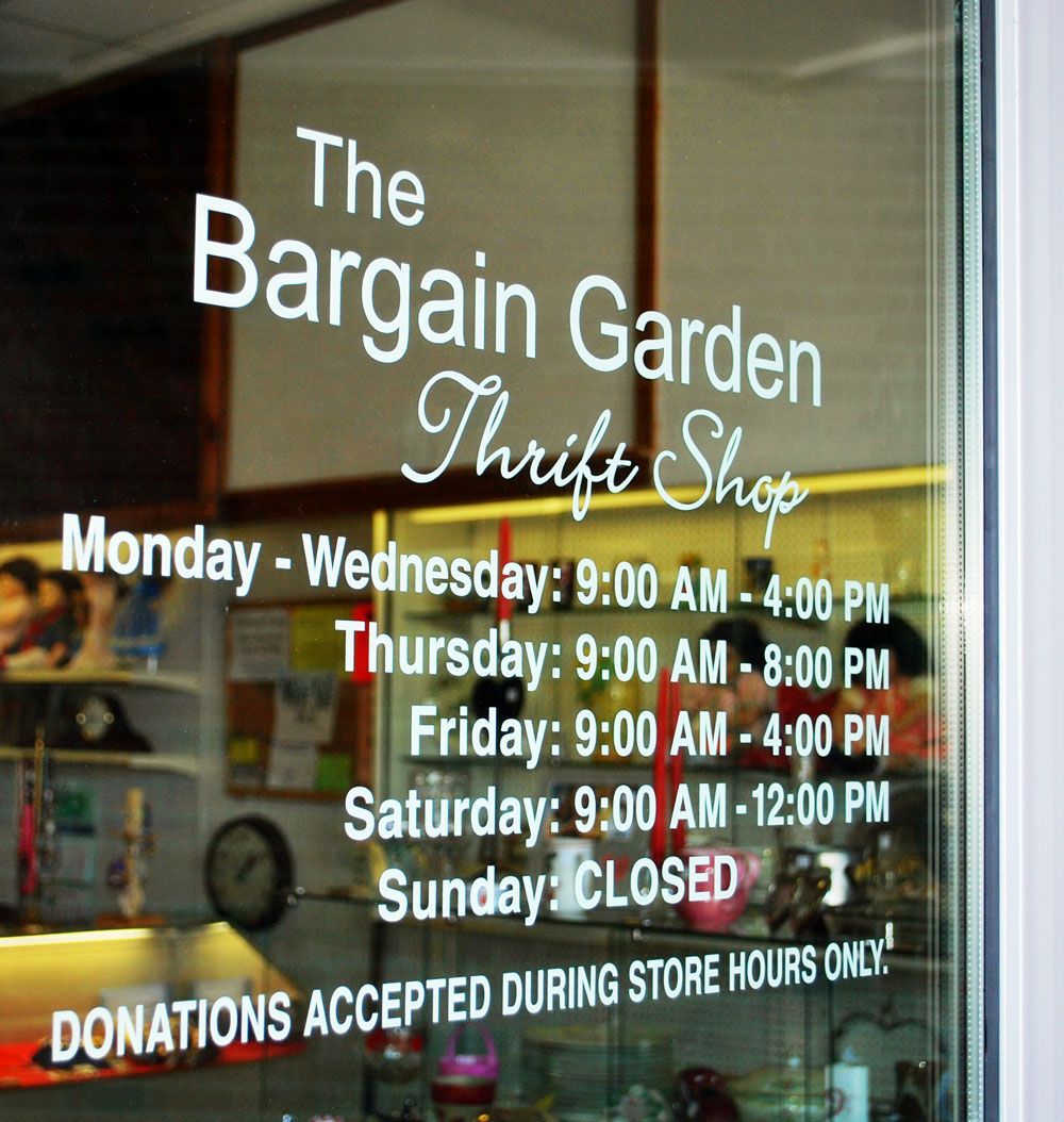 Entry door of the Bargain Garden Thrift Shop with hours listed