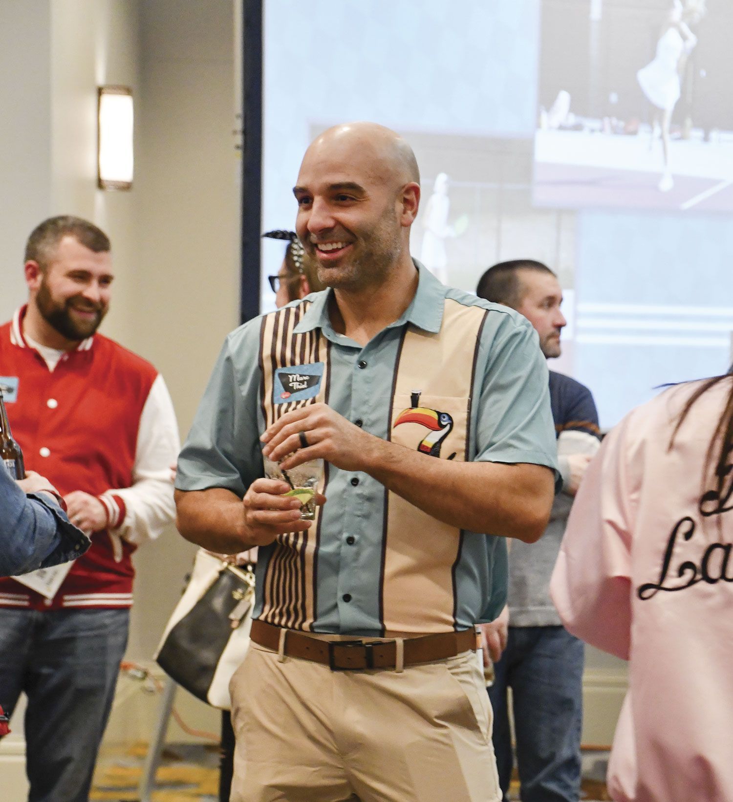 Male FoxFest attendee walking, holding a beverage, and smiling