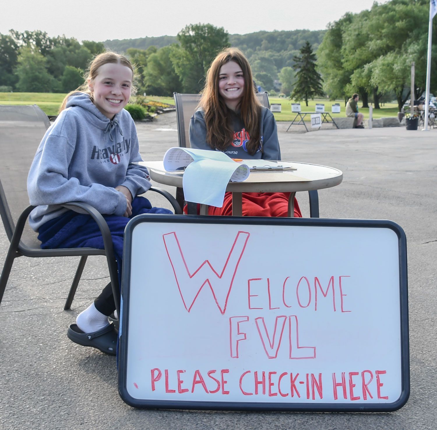 Two high school volunteers at a table to welcome golfers to the event.