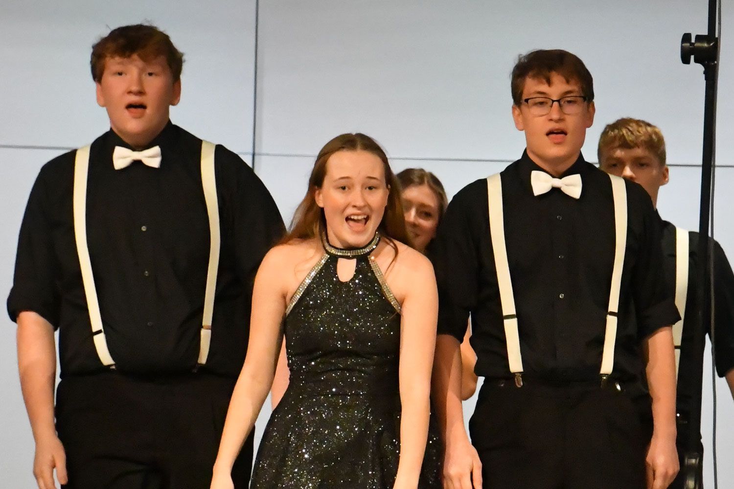 Five of the Choraliers singing and dancing on stage