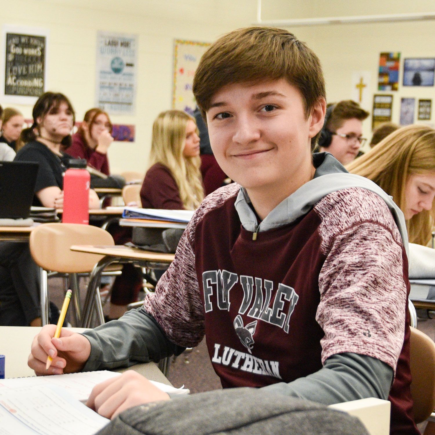 Smiling boy working at a desk in study hall