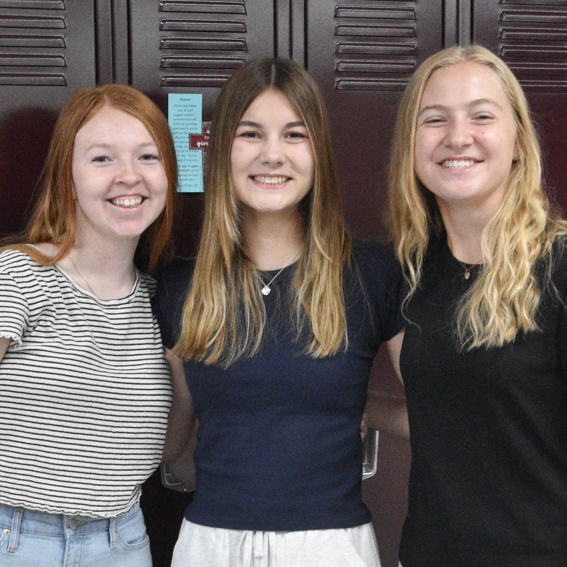 Three smiling girls in front of the lockers